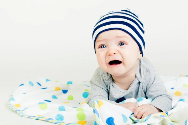 Carino bambino a strisce cappello sdraiato su una coperta — Foto Stock