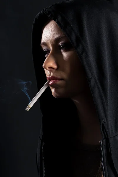 Young woman on a black background smoking a cigarette — Stock Photo, Image