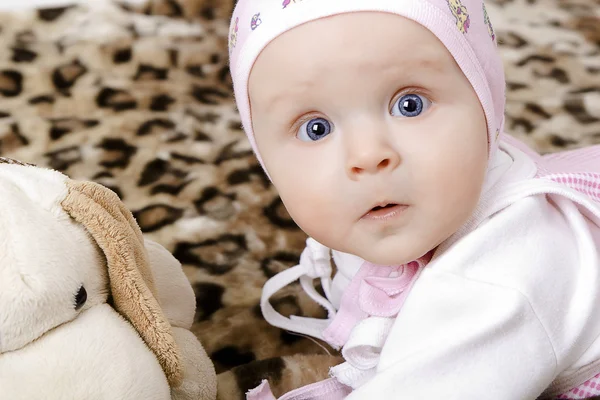 Bébé surpris dans une casquette avec un jouet doux — Photo