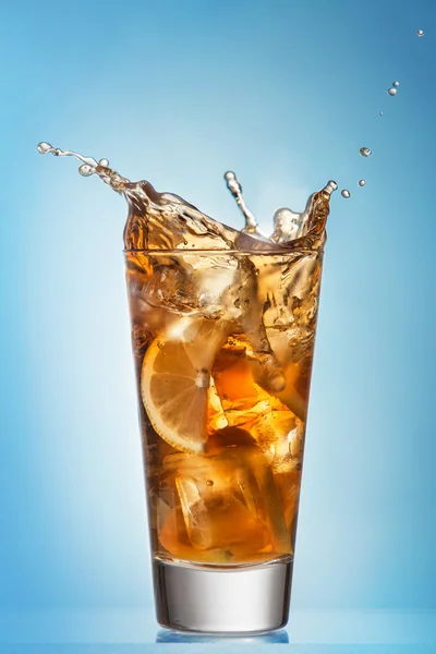 Glass of splashing iced tea with lemon — Stock Photo, Image