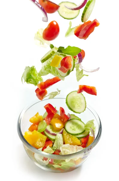 Fresh vegetables falling into the glass bowl — Stock Photo, Image