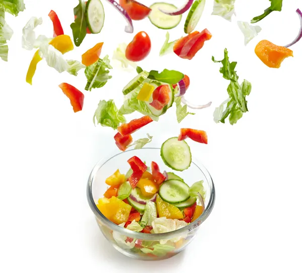 Fresh vegetables falling into the glass bowl — Stock Photo, Image