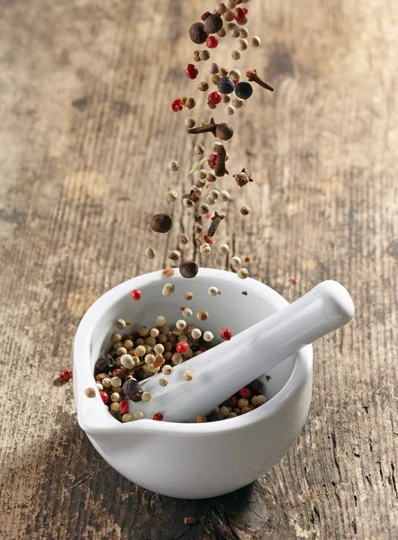 Varias especias que caen en mortero y pestle — Foto de Stock