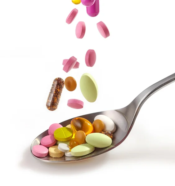 Various pills falling into spoon — Stock Photo, Image