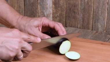 Adam patlıcan kesiyor. Yan görüş. 4K UHD video görüntüsü 3840X2160.