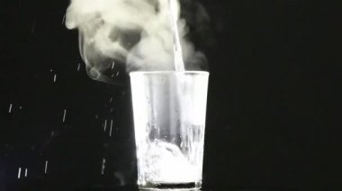 Kaynar su bardağa dökülür. Buhar ve kabarcıklar arka planda açıkça görülebilir. 4K UHD video görüntüsü 3840X2160.