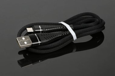 Siyah akrilik arka planda akıllı telefonu şarj etmek için siyah USB kablosu. Yüksek çözünürlüklü. Tam alan derinliği.