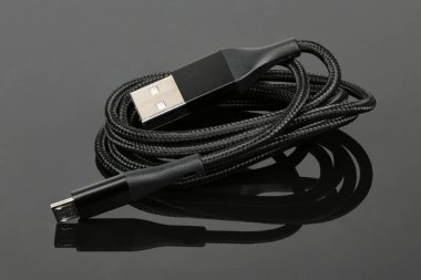 Siyah akrilik arka planda akıllı telefonu şarj etmek için siyah USB kablosu. Yüksek çözünürlüklü. Tam alan derinliği.