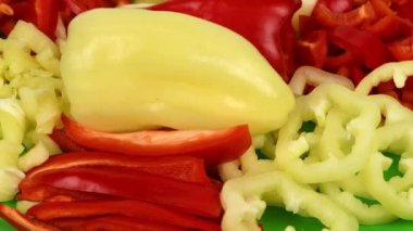 Sarı ve kırmızı dolma biberler farklı şekillerde kesilir. Sağlıklı gıda konsepti. Sebzeleri salataya hazırlıyorum. Döngü hareketi. Yan görüş. Rotasyon 360. 4K UHD video görüntüsü 3840X2160.