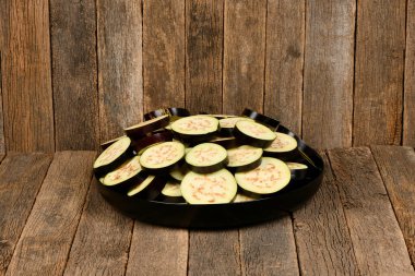 Olgun sulu patlıcan. Koyu ahşap arka planda patlıcanı siyah tabakta dilimle. Yüksek çözünürlüklü. Tam alan derinliği.