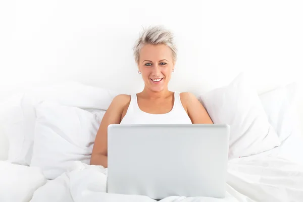 Beautiful blonde woman using a laptop and smiling — Stock Photo, Image