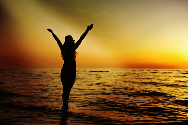 Mujer feliz saltando en la puesta del sol del mar —  Fotos de Stock