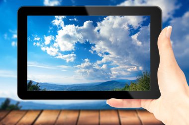 iPad reklam için elinde. Mavi gökyüzü ve bulutlar monitör