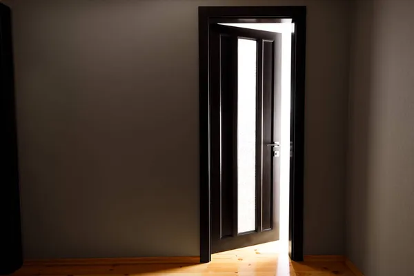 Ljuset som uppenbarar sig genom halvöppna dörren i huset — Stockfoto