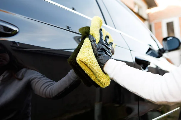 여자들은 자동차를 닦고 , 마이크 로 섬유 천 을 사용하고, 구두약을 사용하여 자동차의 몸체를 윤으로 닦는다. — 스톡 사진