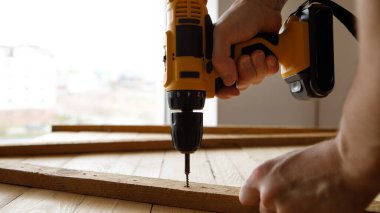 Mavi üniformalı tamirci otomatik tornavidayla çalışıyor. Ev yenileme konsepti.