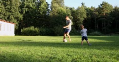 Baba ve oğul doğada futbol oynuyorlar.