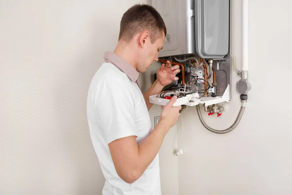 Υδραυλικός αποδίδει Προσπαθώντας να διορθώσετε το πρόβλημα με τον οικιακό εξοπλισμό θέρμανσης. Επισκευή λέβητα αερίου — Φωτογραφία Αρχείου