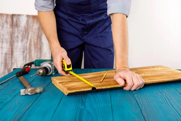 Handyman in blue uniform works with electricity automatic screwdriver. House renovation conception. — Stock Photo, Image