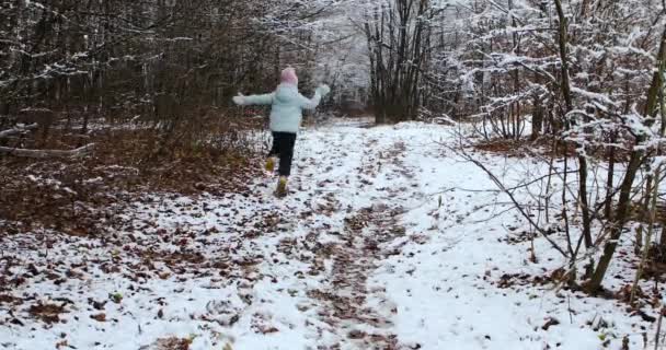 美しい女の子は雪の冬の森の中で逃げます — ストック動画