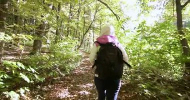 Kız bir sırt çantası ile sonbahar ormanda yürür