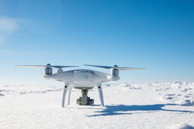 Güneşli kış gününde karla kaplı bir dron tarlanın üzerinde uçuyor.