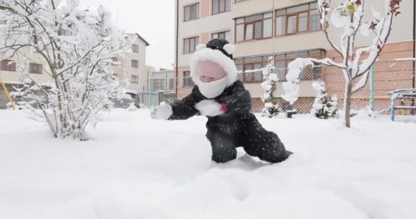 Chica haciendo muñeco de nieve en brillante lugar cubierto de nieve — Vídeos de Stock