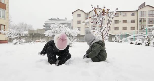 Enfants faisant bonhomme de neige à l'endroit enneigé lumineux — Video