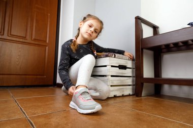 Küçük kız ayakkabılarını giyer.