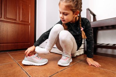 Küçük kız ayakkabılarını giyer.