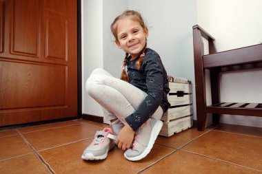Küçük kız ayakkabılarını giyer.