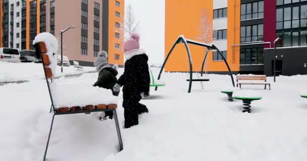 Barn leker med snö på lekplatsen — Stockvideo