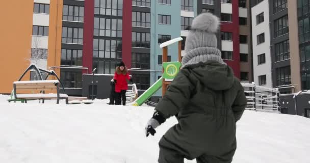Barn leker med snö på lekplatsen — Stockvideo