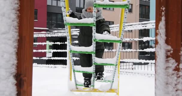 Дети играют со снегом на детской площадке — стоковое видео