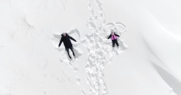Feliz familia mujer y hombre se encuentra en la nieve y hace un ángel — Vídeos de Stock