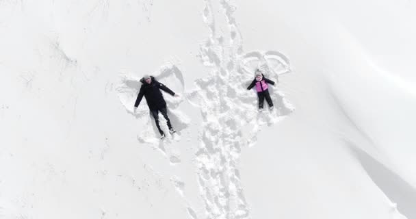 Feliz mulher de família e homem jaz na neve e faz um anjo — Vídeo de Stock