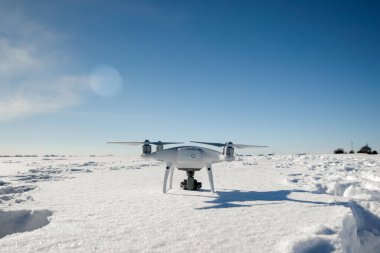 Güneşli kış gününde karla kaplı bir dron tarlanın üzerinde uçuyor.