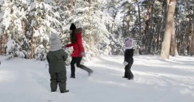 happy mother and child playing in the snow with a sledge in a sunny winter day