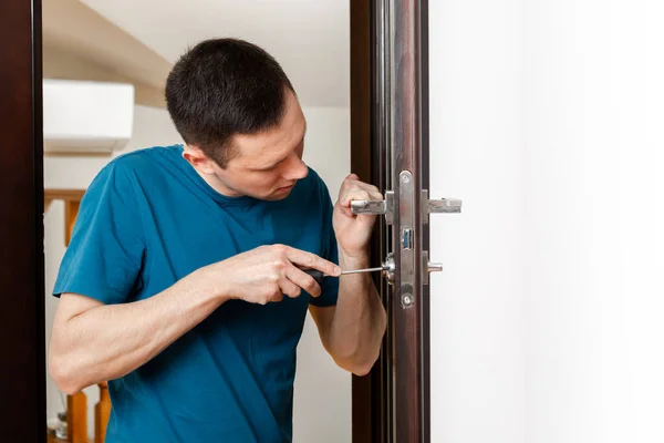 Un hombre reparando una perilla de la puerta. cerrajero que fija una puerta de madera — Foto de Stock