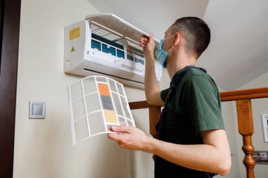 Erkek teknisyen içeride klimayı temizliyor..