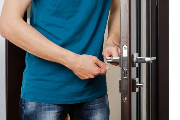 ドアノブを修理する男。木製のドアを固定する錠前屋 — ストック写真
