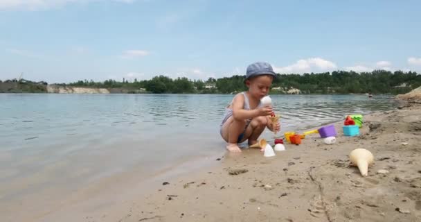Çocuklar güneşli bir yaz gününde kumların üzerinde nehir kıyısında oynarlar. — Stok video