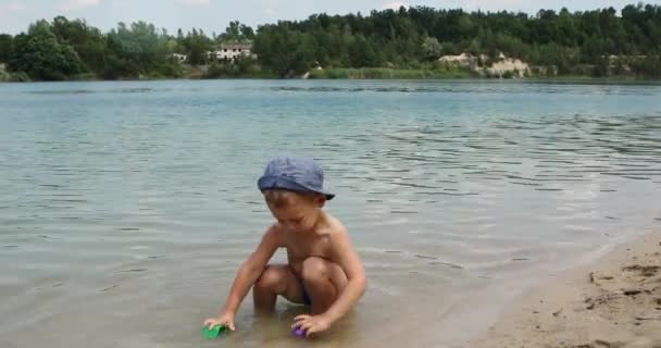 Kinder spielen an einem sonnigen Sommertag am Ufer des Flusses im Sand — Stockvideo