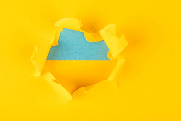 Geel en blauw gat in het papier met gescheurde zijkanten. concept oorlog in Oekraïne — Stockfoto