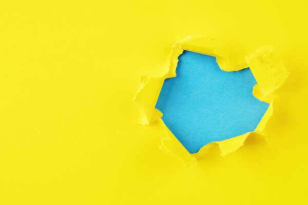 Желтая и синяя дыра в бумаге с разорванными сторонами.