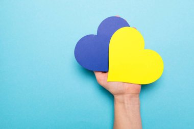 Savaş falan yok. Kadın ellerinde kağıttan yapılmış mavi ve sarı kalp. 