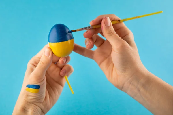 Huevo de Pascua en mano de mujer en los colores de la bandera de Ucrania como concepto para la guerra Ucrania —  Fotos de Stock