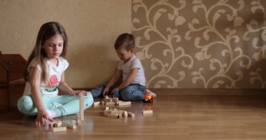 Çocuklar çocuk odasının zemininde tahta bloklarla oynarlar..