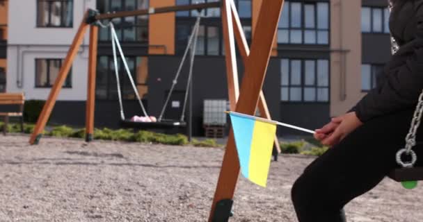 Κορίτσι με τη σημαία του Ουκρανού σε μια κούνια κοντά στην παιδική χαρά — Αρχείο Βίντεο