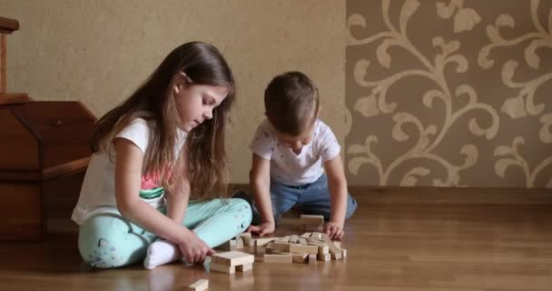 Los niños juegan con bloques de madera en el suelo de la habitación de los niños. — Vídeos de Stock